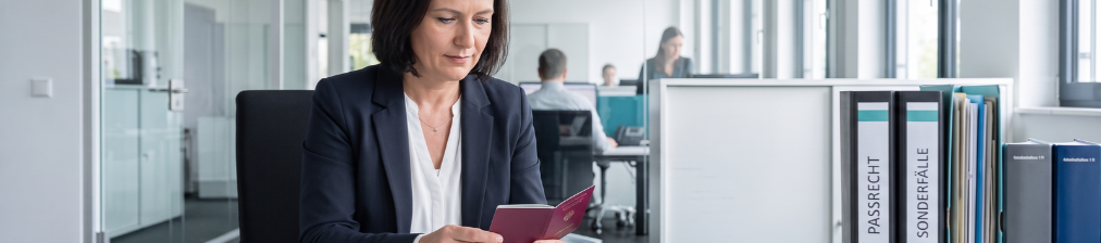 Frau hält ein Ausweisdokument an einem Schreibtisch in einem hellen Büro
